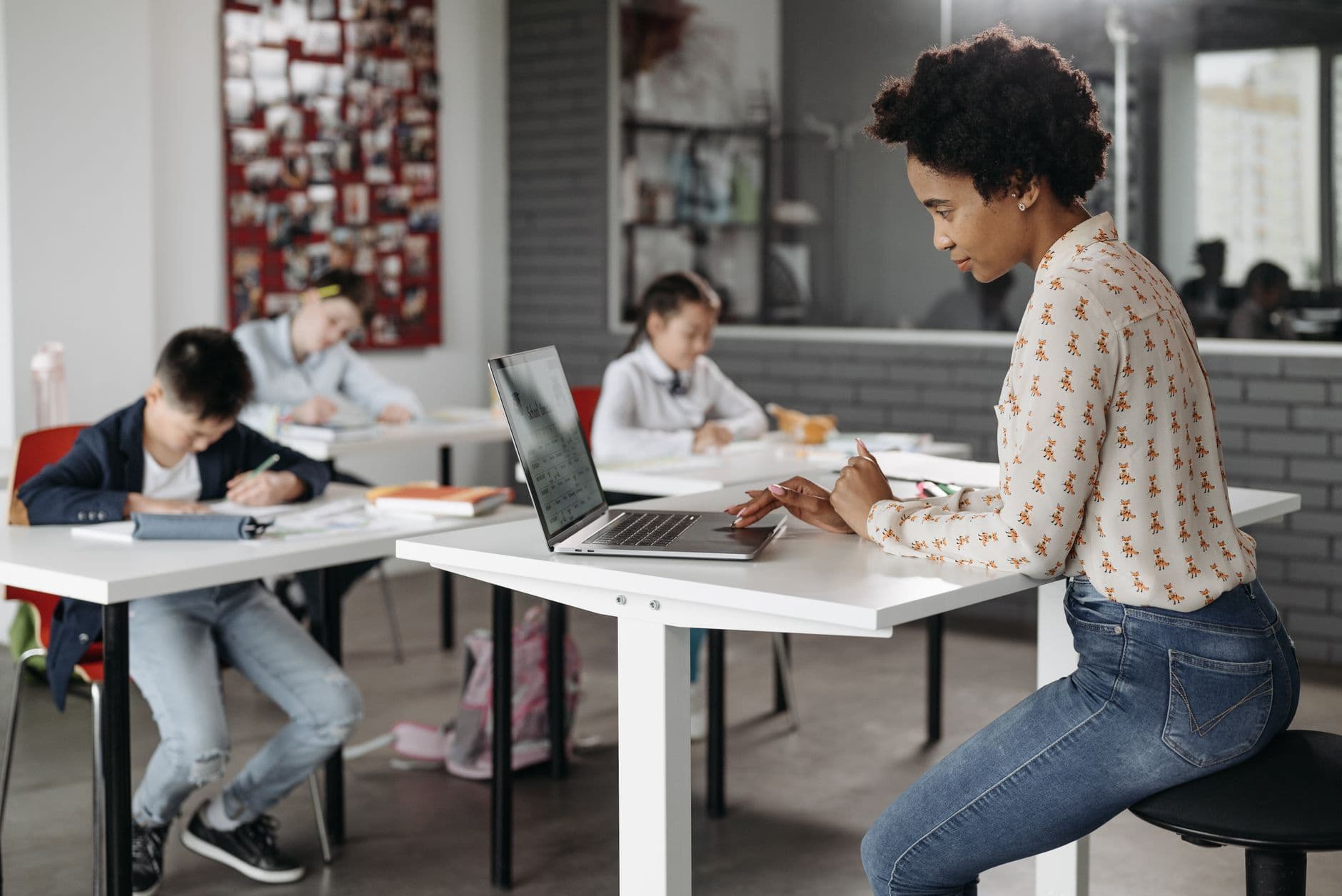 Focused teacher with students working at desks in an indoor classroom environment.