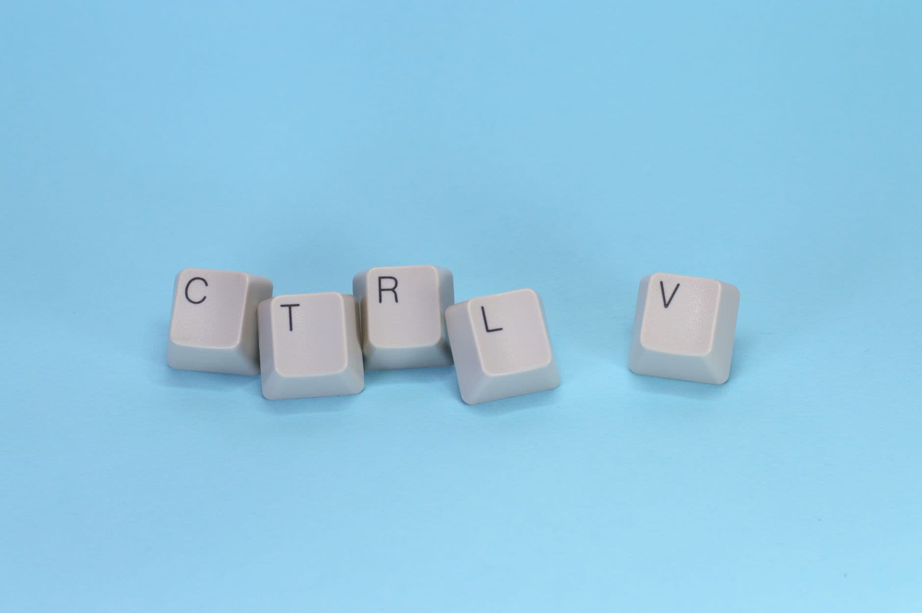Close-up of CTRL V keyboard keys on a blue background. Minimalist tech concept.