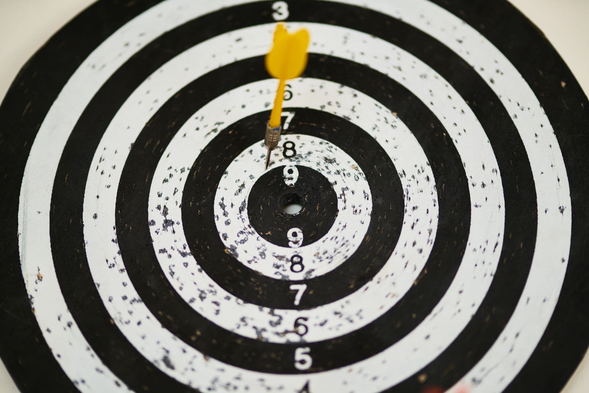 Close-up of a dart hitting the bullseye on a black and white target board symbolizing success.